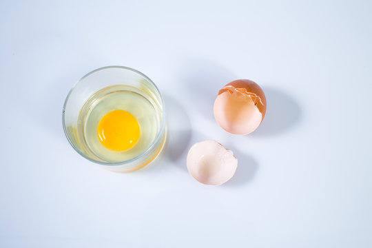 Raw chicken egg and Cracked egg shells in glass bowl isolated on white background