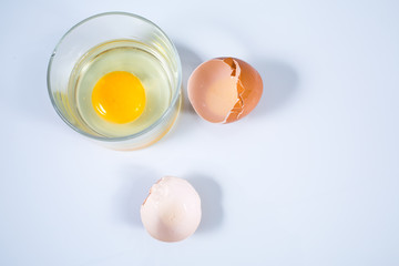 Raw chicken egg and Cracked egg shells in glass bowl isolated on white background