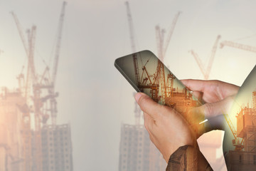 double exposure of woman hand hold and touch screen smartphone, cellphone, construction crane,...