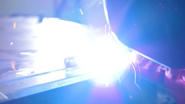 Slow motion welding. Welder worker welding metal. Bright electric arc and sparks during manufacture of metal equipment. HD.