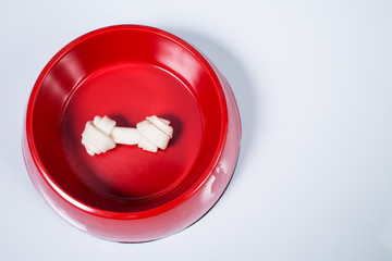 Dog bone in feeding bowl isolated on white background