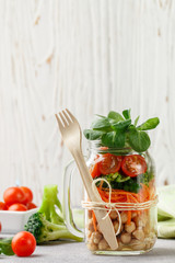 Healthy vegetarian Mason Jar salad with chickpeas and vegetables - carrots, broccoli, tomatoes, greens. Healthy eating, diet, detox. Selective focus