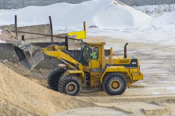 Yellow excavator loads sand