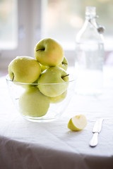Granny smith apples in a big glass bowl on white background