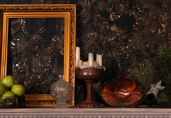 Marble mantelpiece with wooden frame, apples, cakes, brass candlestick and pine branch with star on it