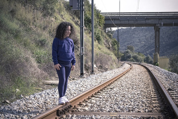 Niña jugando feliz en las vías del tren.