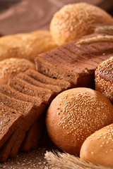 Assortement of bread on burlap on the wooden table. Slices of bread and roll.