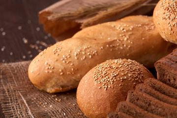 Assortement of bread on burlap on the wooden table. Slices of bread and roll.