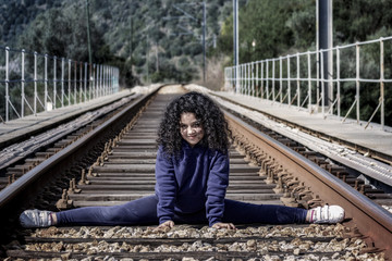 Haciendo gimnasia en las vías del tren. Niña jugando feliz en las vías del tren.