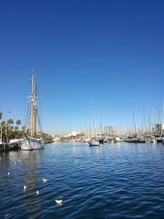 Fototapeta na wymiar BARCELONA, SPAIN - FEBRUARY 9, 2017 : Sailboats parked in Barcelona harbour during a sunny day.