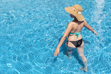 Woman in hat walking in the swimming pool