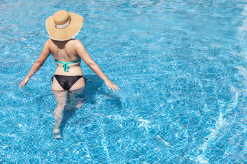 Woman in hat inside of the swimming pool