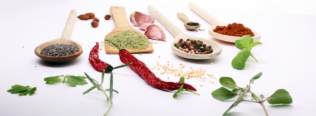 Various herbs and spices in wooden spoons. Flat lay of spices ingredients chilli ,pepper, garlic,dries thyme, nutmeg,rosemary, sweet basil and matcha on white background