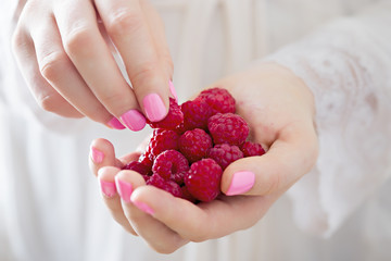 Woman holding raspberries in hands 