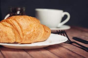 croissant in a plate and a cup with a drink in the background