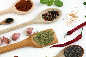 Various herbs and spices in wooden spoons. Flat lay of spices ingredients chilli ,pepper, garlic,dries thyme, nutmeg,rosemary, sweet basil and matcha on white background