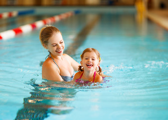 Mother teaches child to swim in pool