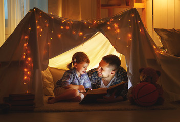 happy family father and child daughter reading a book  in  tent at home. - Powered by Adobe