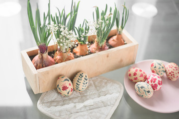 Fototapeta na wymiar plate with polka dot easter eggs and wooden vase with green grass on background