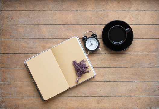 photo of opened notebook, bunch of lavender, alarm clock and cup of coffee on the wonderful wooden brown background