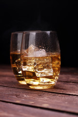 glass of whiskey with ice on a wooden