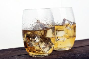 glass of whiskey with ice on a wooden