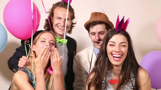 Group of beautiful young friends having a great time in party photo booth 