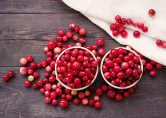 Fresh juicy cranberry in wooden round bowls on a table, close up