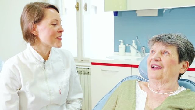 Close up of young female dentist and elderly female patient talking