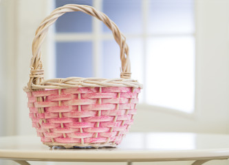 Wicker basket on white table on window background