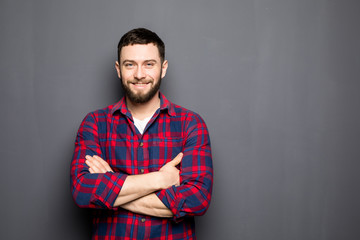Obraz premium Portrait of handsome young man in casual shirt keeping arms crossed and smiling