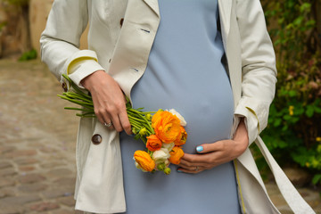 Closeup of pregnant woman with flowers