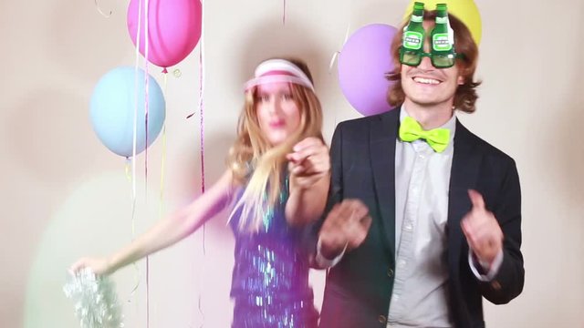 Cheerful beautiful woman and smiling man dancing in party photo booth, graded