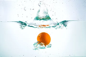 Poster Orange in a stream of water on a white background, studio light © oleghz