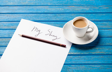 photo of paper My story and cup of coffee on the wonderful blue wooden background