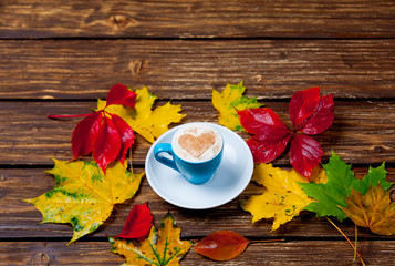 photo of cup of coffee and autumn leaves on the wonderful brown wooden background