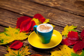 Naklejka na ściany i meble photo of cup of coffee and autumn leaves on the wonderful brown wooden background