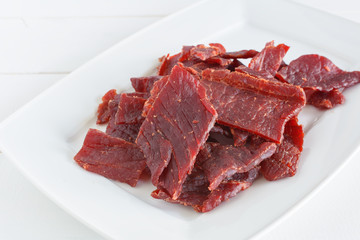 Beef jerky pieces on white dish.