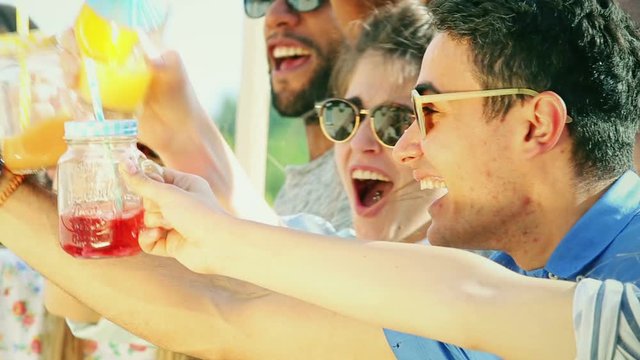 Close up of cheerful friends laughing and toasting at rooftop party, graded