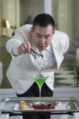 Chinese Barman is making cocktail at night club.