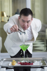 Chinese Barman is making cocktail at night club.