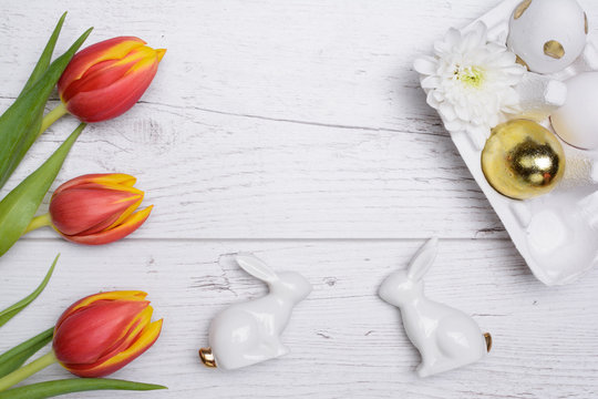 Easter eggs and tulips over wooden background.