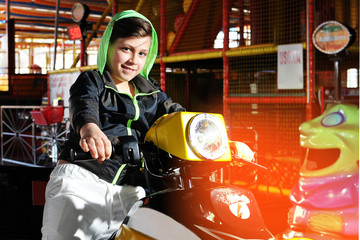 smiling boy, casual sitting on a motorcycle, he is wearing white pants, green shirt, colorful background