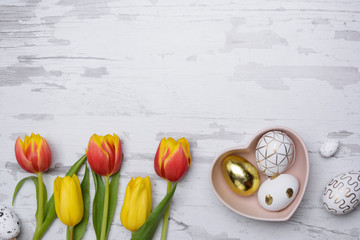 Easter eggs and tulips over wooden background.