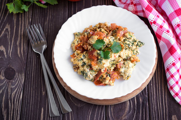 Fried eggs with tomato on dark wooden table