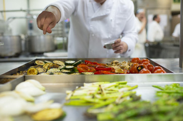 Hand adding salt to vegetables