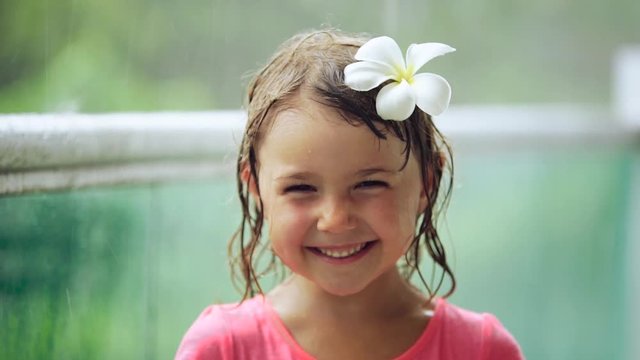 Portrait 5 year old girl having fun during a heavy tropical rain