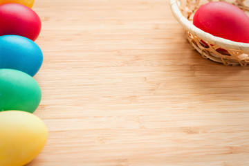 Multicolored easter eggs, and basket with eggs on a textured wooden background. The concept of a holiday and a happy Easter. with space for text
