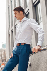 Young man dressed formal resting outdoors near business center. Serious young man in city.