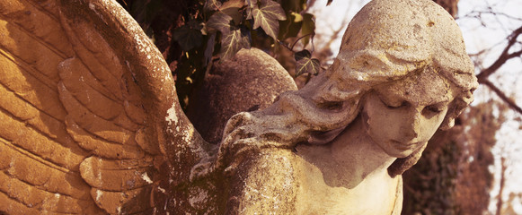 Vintage image of a sad angel on a cemetery against the background of leaves
